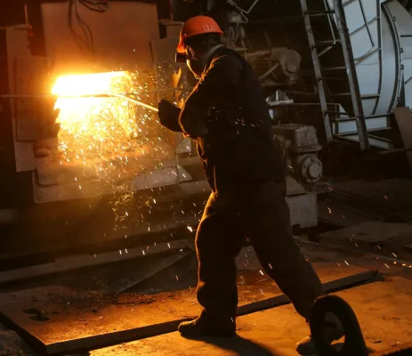 man stookt vuur op in metalen ketel